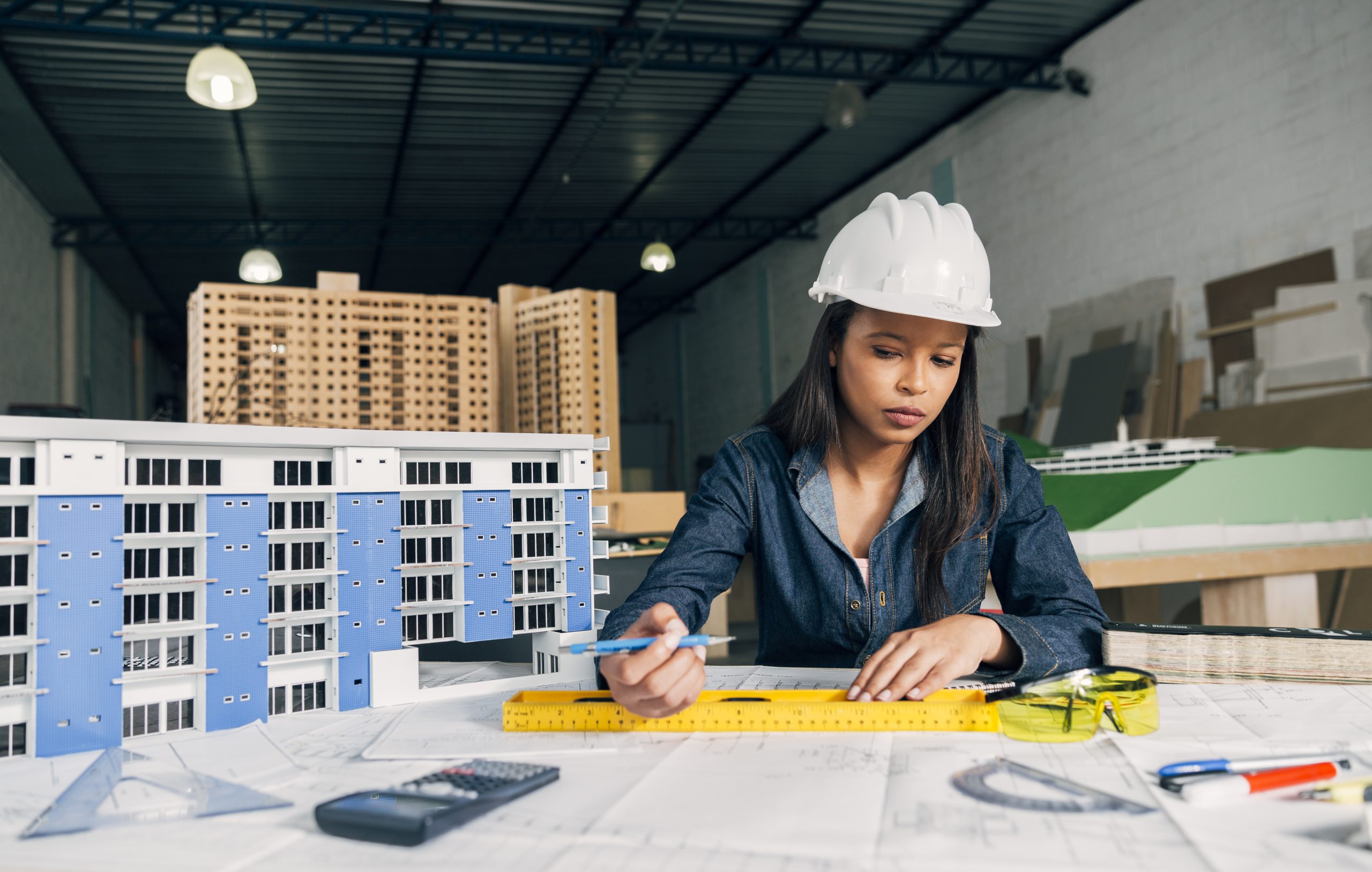 Femme afro-américaine dans un casque de sécurité travaillant près du modèle de construction