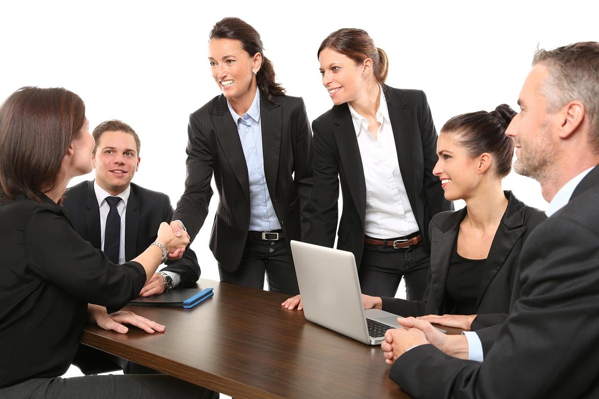 Groupe de professionnels en costume réunis autour d'une table de travail avec ordinateur portable