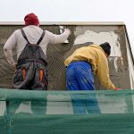Deux ouvriers réparent un mur sur un échafaudage