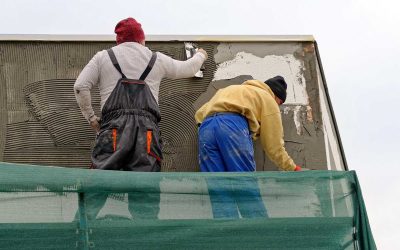 Deux ouvriers réparent un mur sur un échafaudage