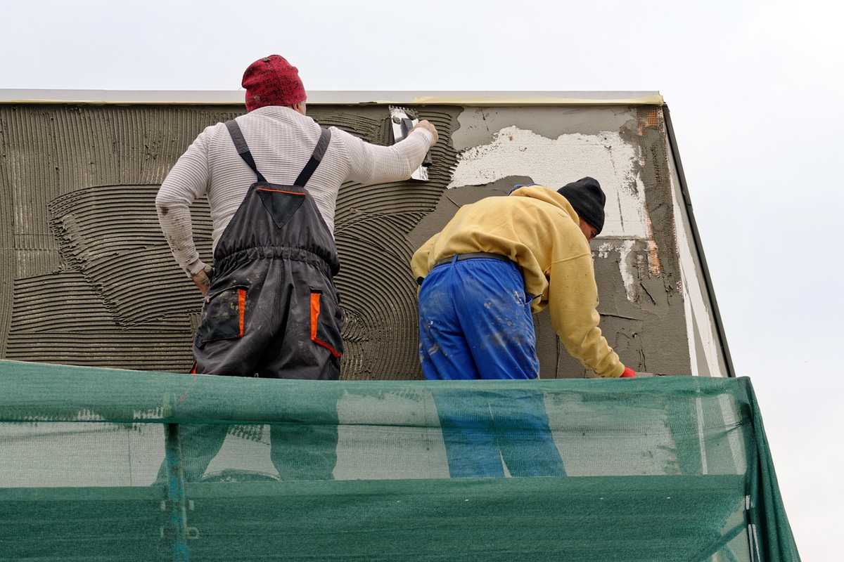 Deux ouvriers réparent un mur sur un échafaudage