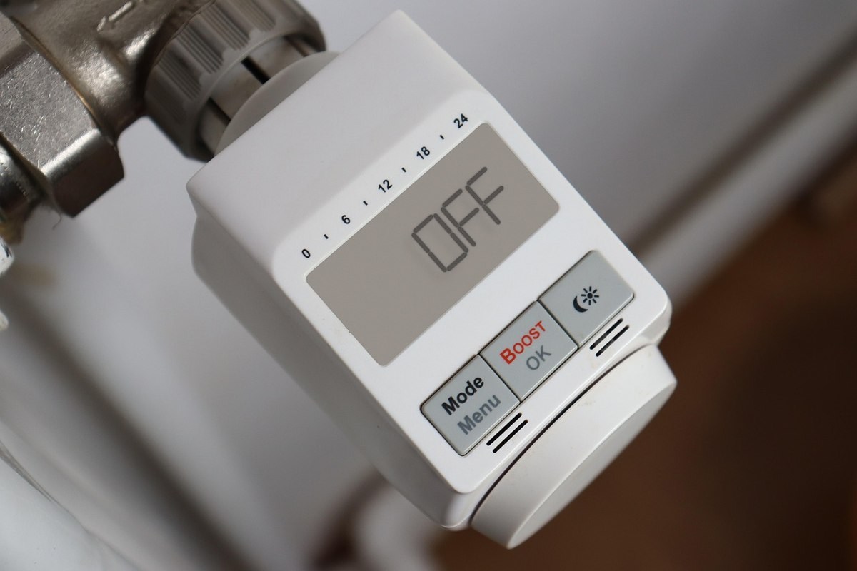 Thermostat digital fixé sur un radiateur, écran OFF, boutons de contrôle visibles Thermostat digital fixé sur un radiateur, écran OFF, boutons de contrôle visibles