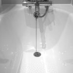 Baignoire blanche avec robinet et tuyau, eau qui coule dans la salle de bain